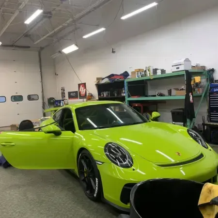 Bright lime green sports car in a garage, with the driver door open.