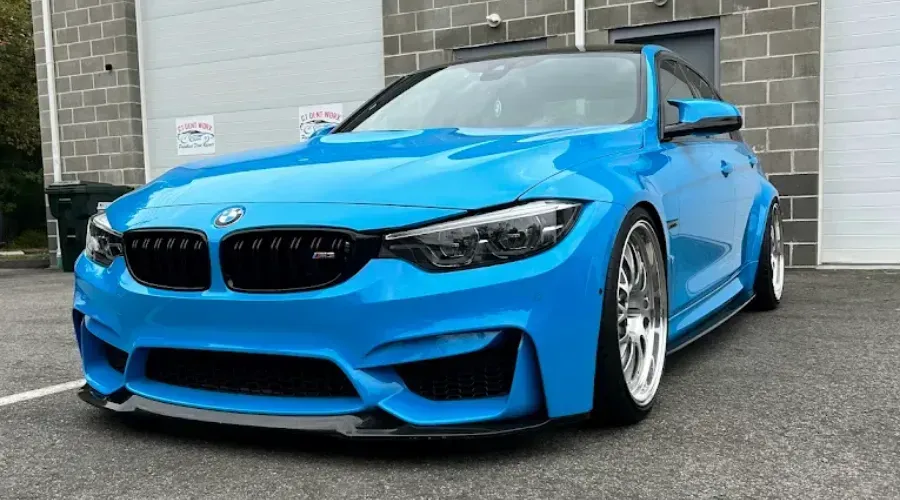 Bright blue BMW sports car parked on a driveway in front of a garage