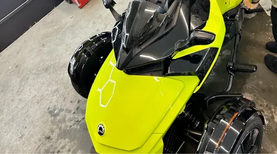 Bright yellow three-wheeled sports motorcycle parked on a garage floor, viewed from above