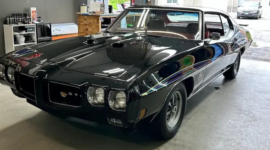 Black classic Pontiac muscle car parked indoors in a garage, front three-quarter view.