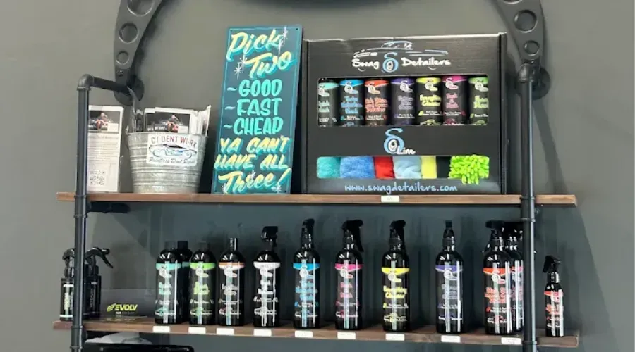 Shelf display of black and colorful bottles with a turquoise sign in a store or studio.