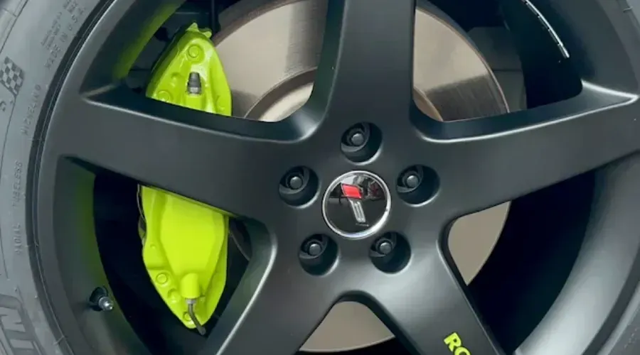 Close-up of a black car wheel with a bright neon green brake caliper and Corvette emblem.