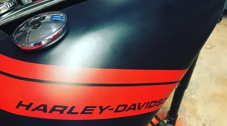 Close-up of a black and red Harley-Davidson motorcycle fuel tank with logo and chrome cap