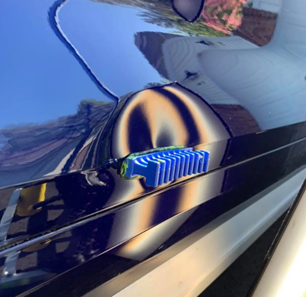 Close-up of a glossy black car door with a blue-and-yellow striped handle reflecting surroundings Close-up of a glossy black car door with a blue-and-yellow striped handle reflecting surroundings