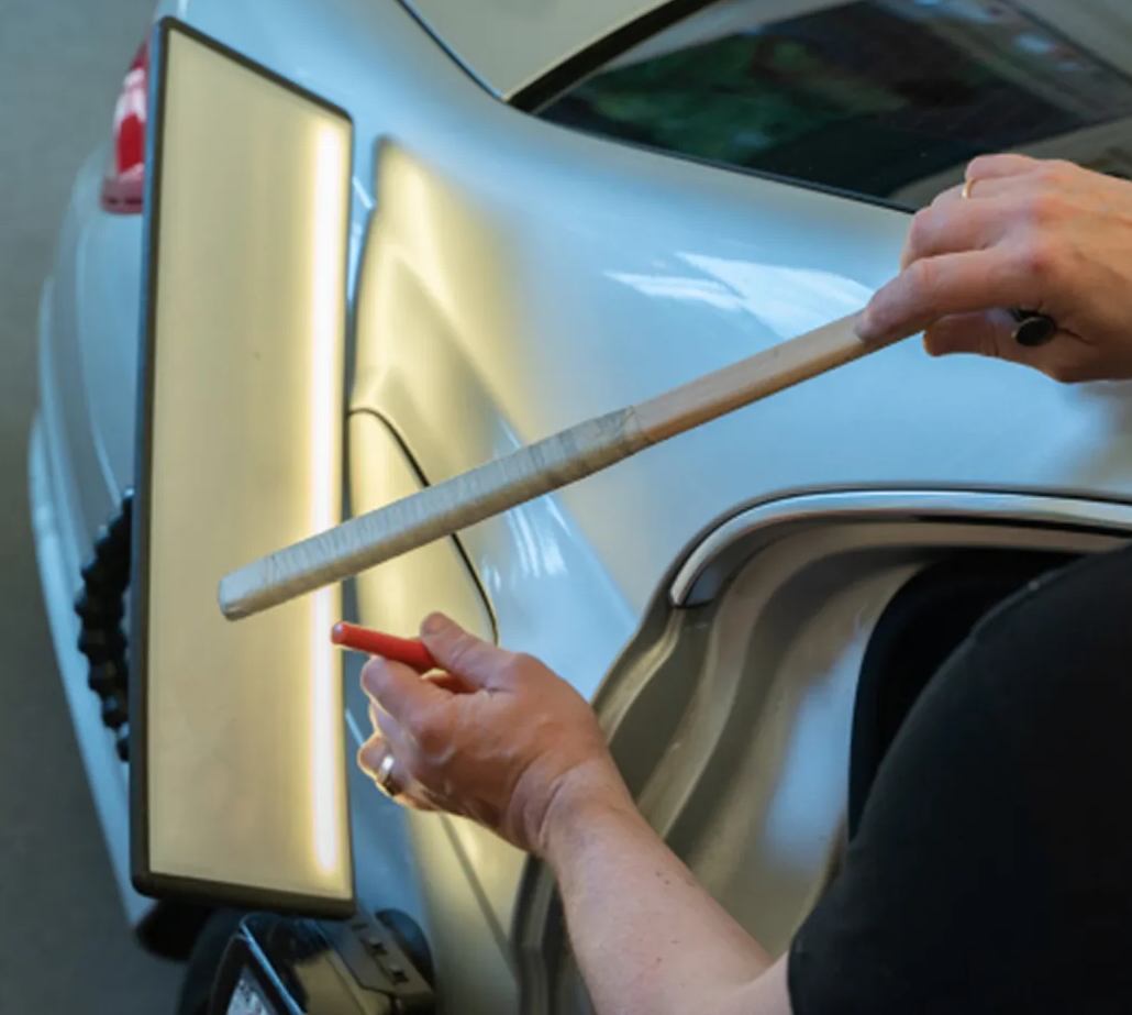 Technician using a squeegee to apply tinted film on a car window