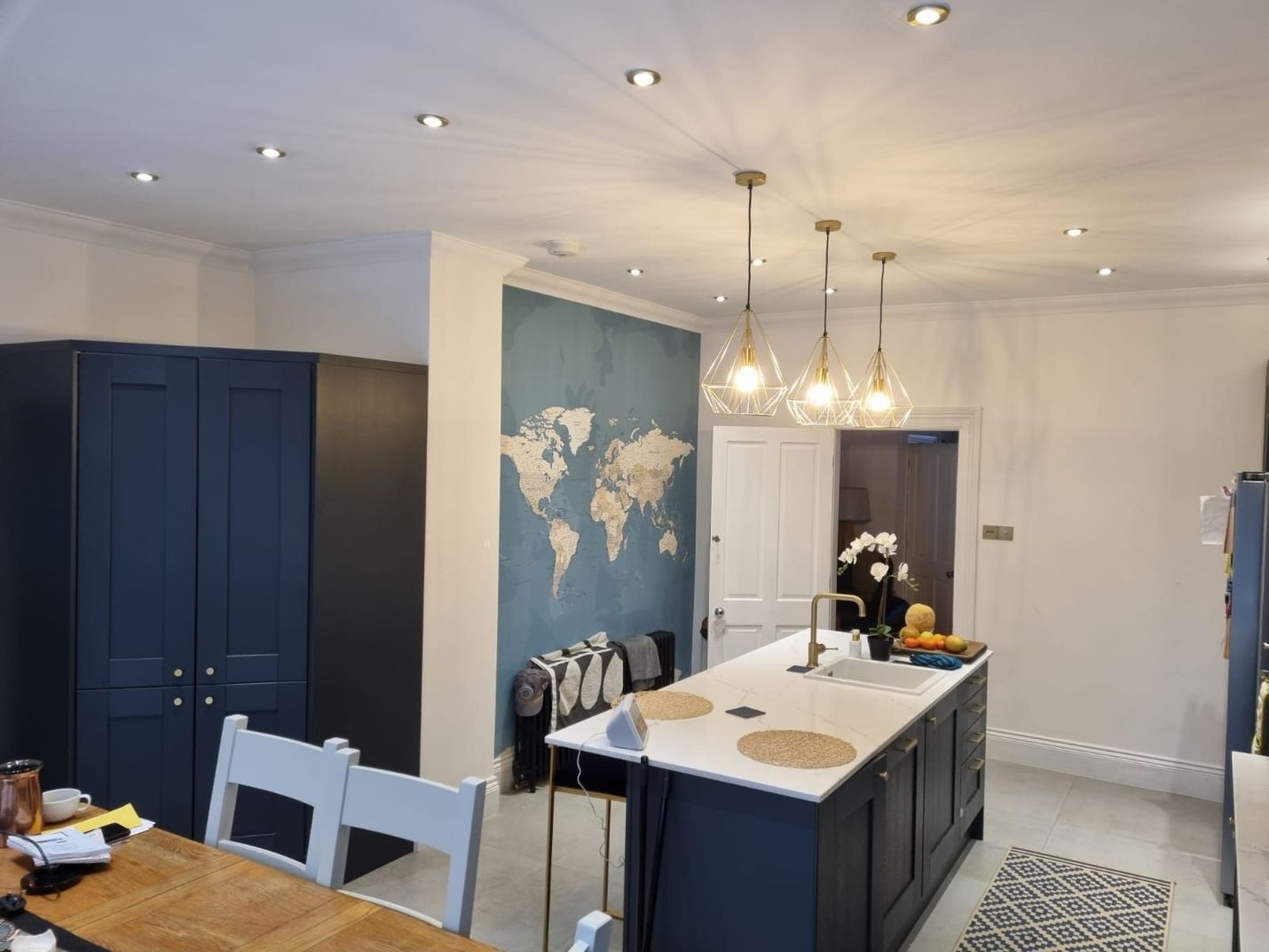 Kitchen with navy cabinets, island, world map art, pendant lights, and recessed lighting.