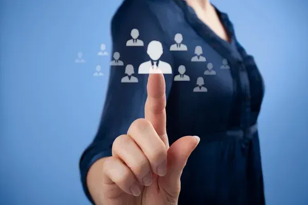 Woman's finger pointing at a human icon, with other similar icons in the background, on a blue background.