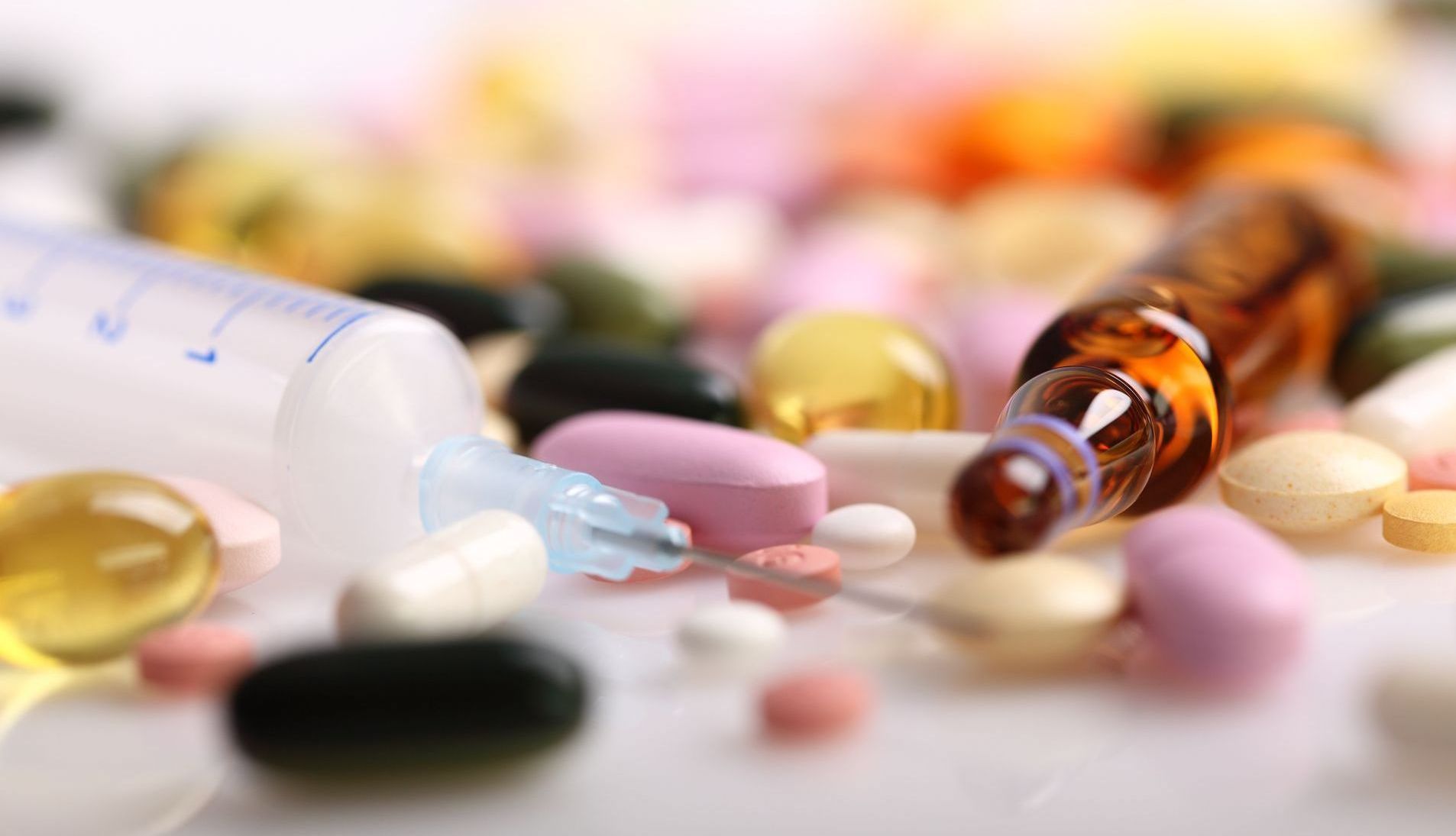 Pills, a syringe, and a vial scattered on a surface; medical supplies.