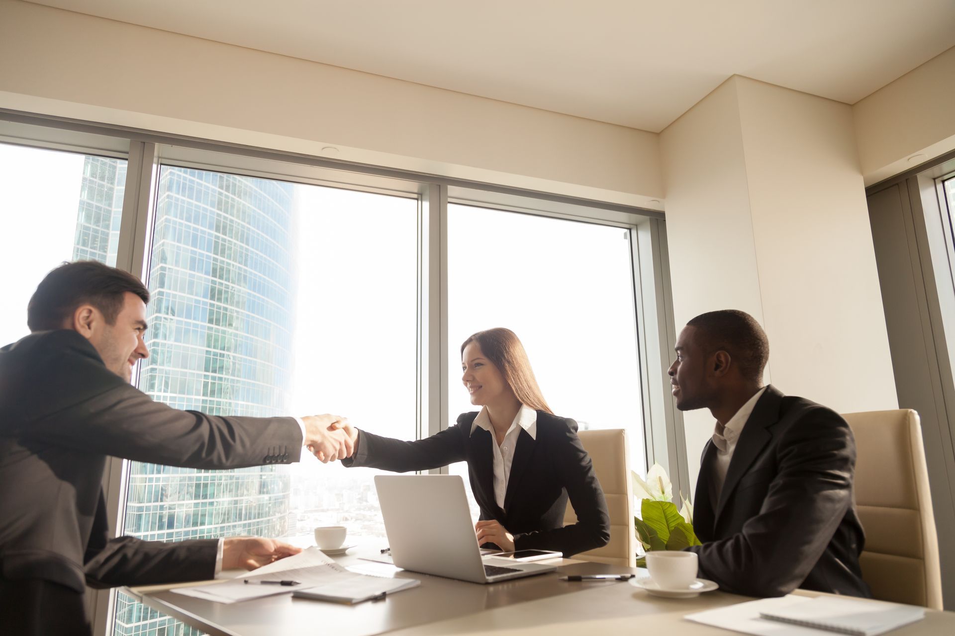 Five people smiling in an office, standing in front of a 