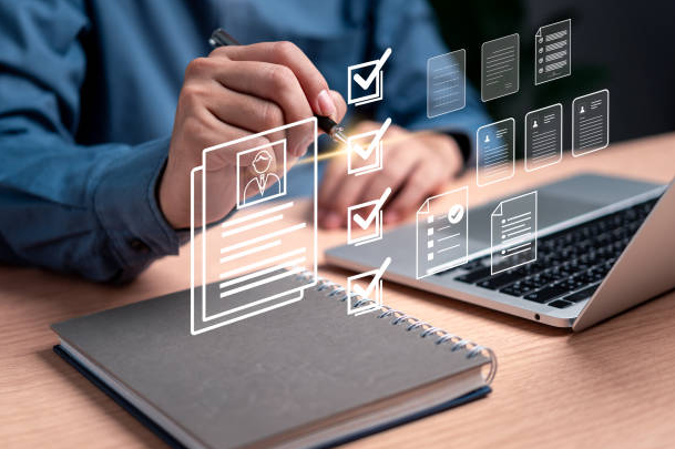 Person reviewing documents on a laptop, with digital checklist icons, on a desk.