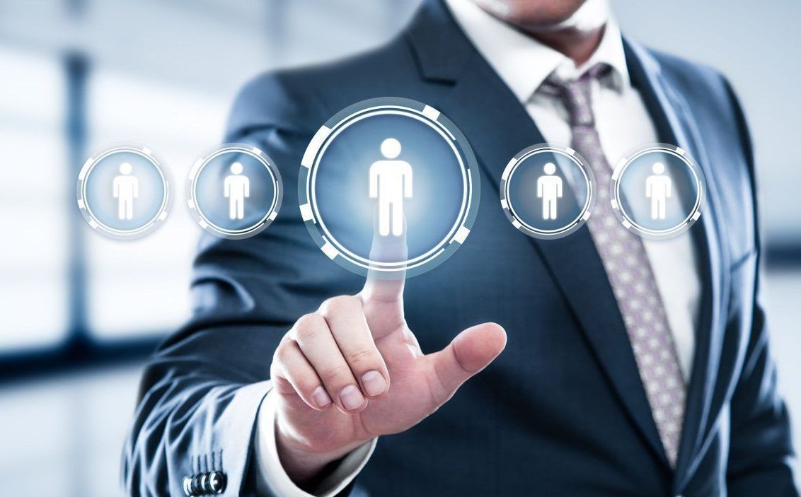 Businessperson in a suit touches a human icon on a digital screen, selecting a candidate.
