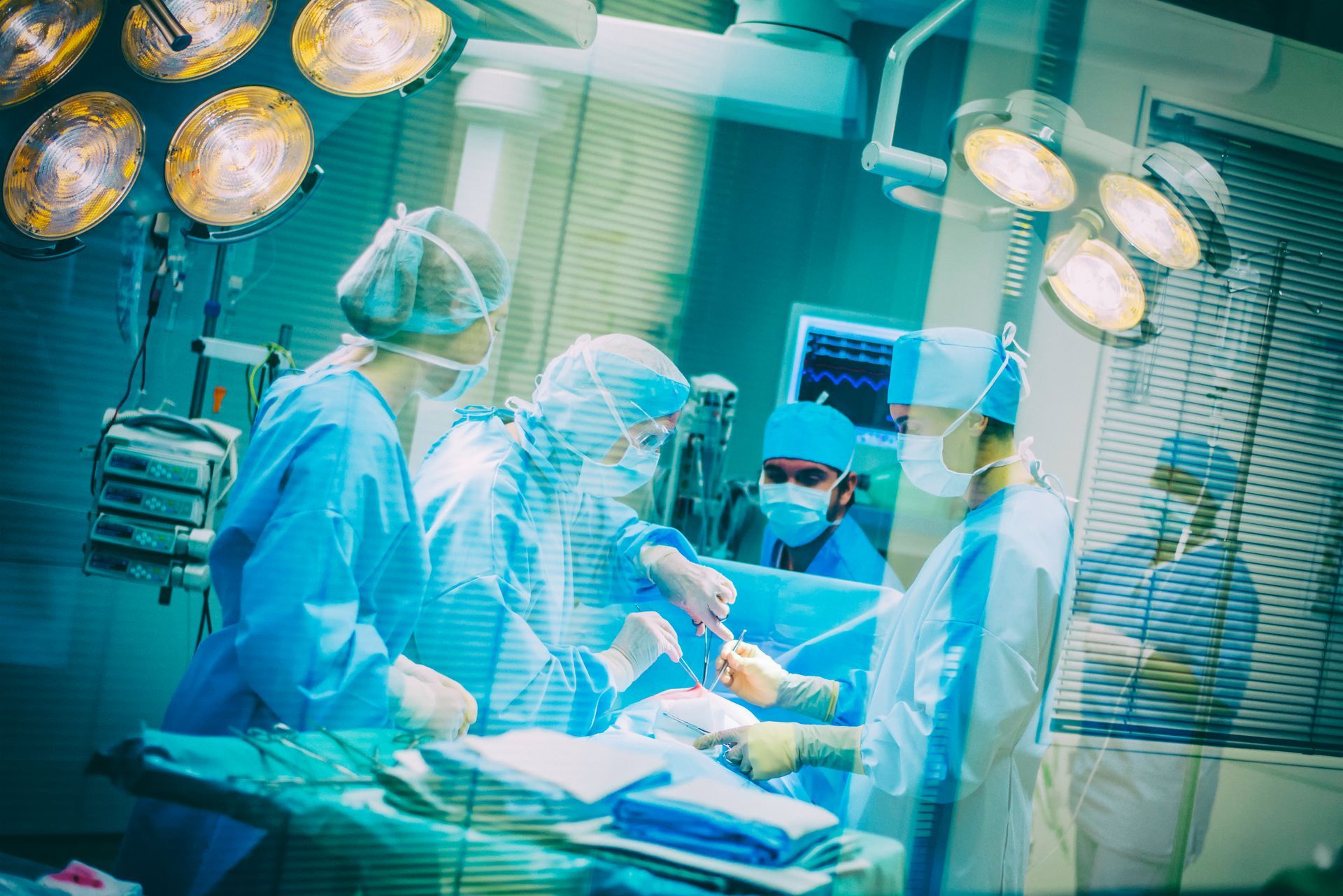 Operating room: Surgeons in blue scrubs operating under bright lights.
