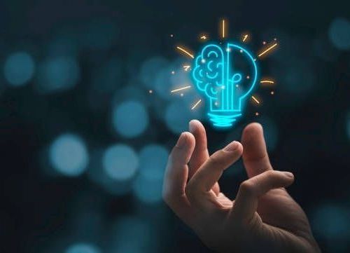 Hand holding glowing lightbulb with brain, suggesting idea/innovation.