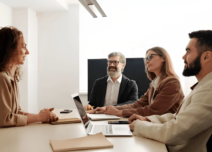 Woman in interview facing panel at table with laptop.
