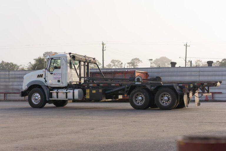 White flatbed tow truck parked in a lot with a long trailer attached