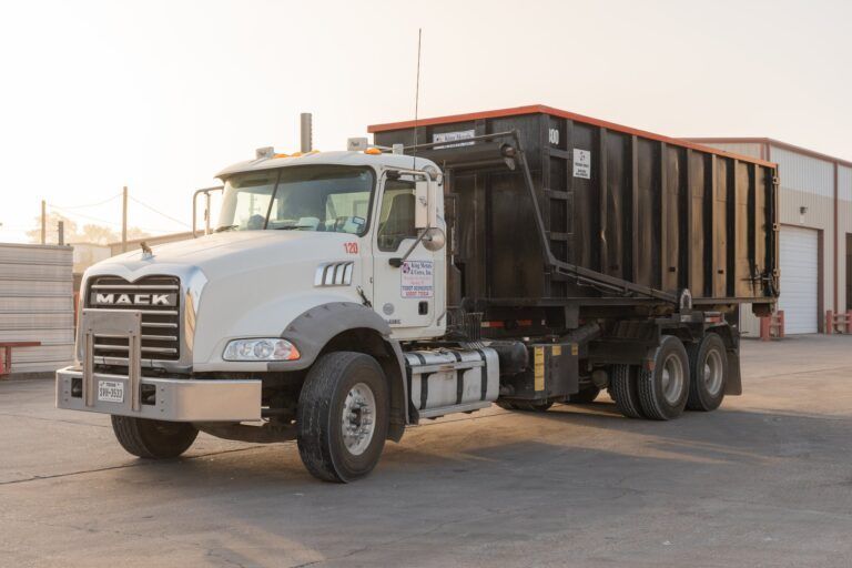 White Mack dump truck parked in an industrial lot at sunset