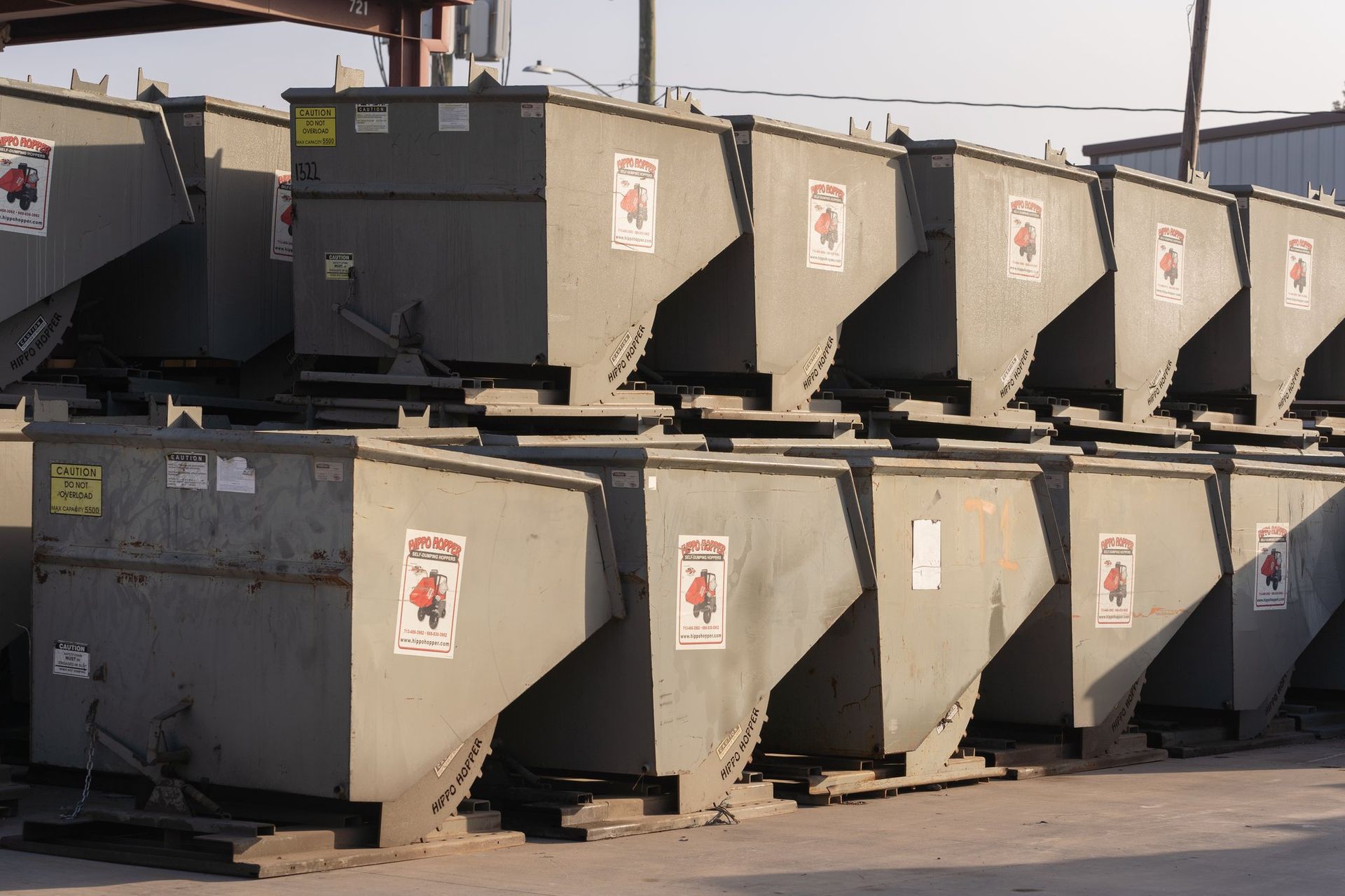 Rows of gray industrial dumpsters stacked outdoors in a lot