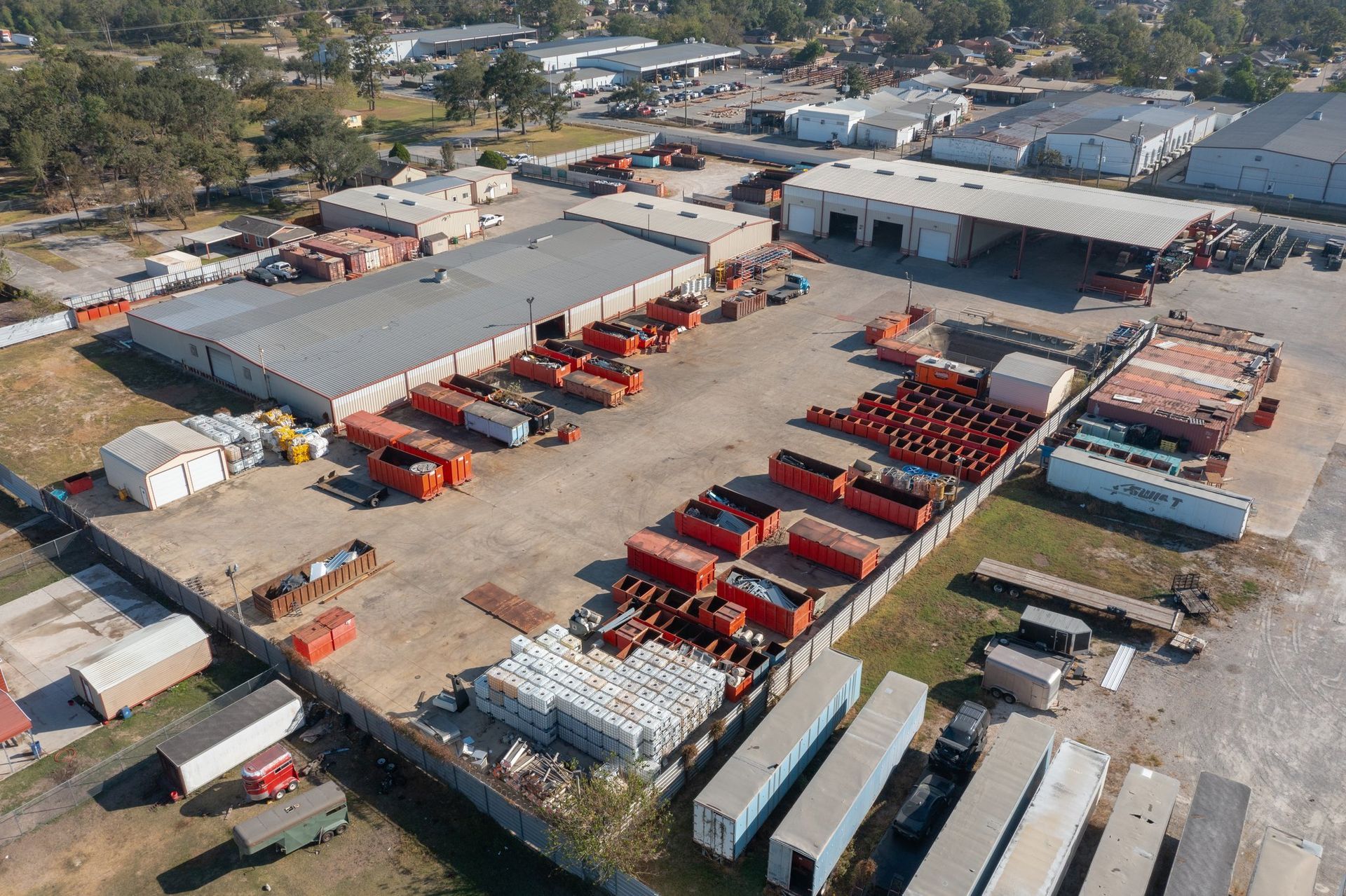 Aerial view of a truck yard with rows of red and white commercial trucks and warehouses