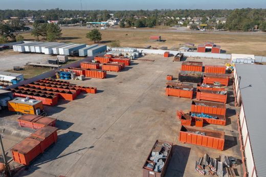 Aerial view of a yard with rows of orange shipping containers and trucks in an industrial area