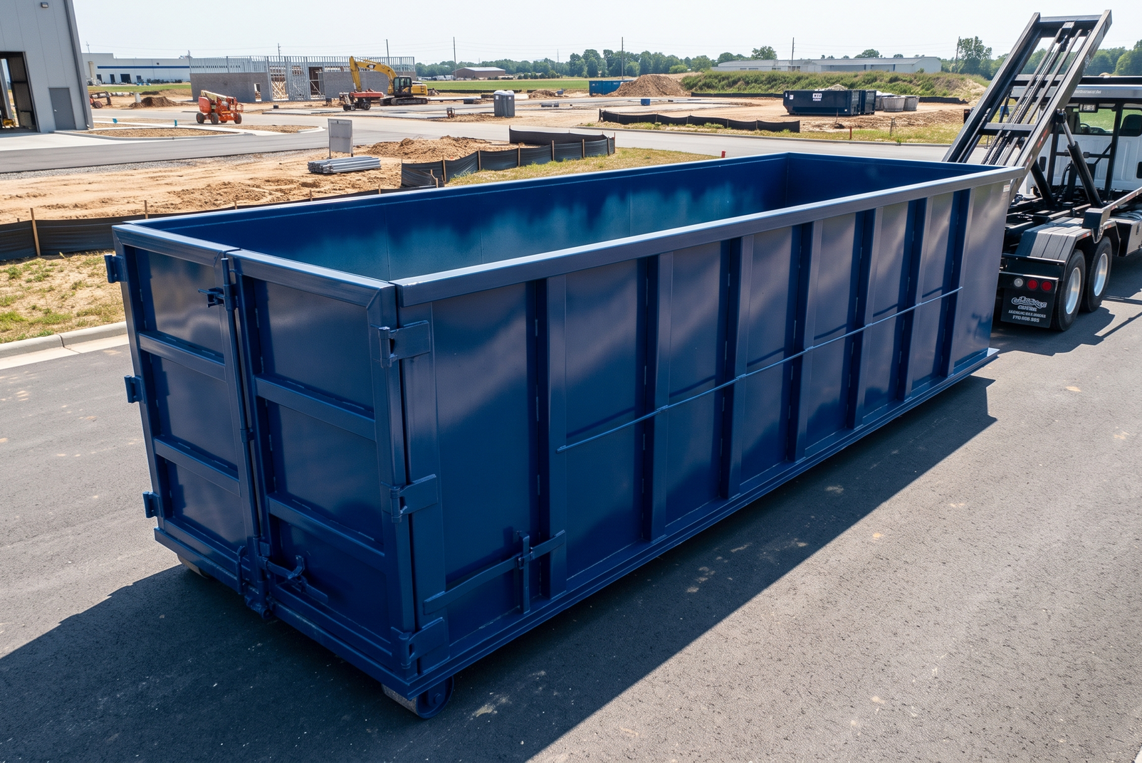 Large blue dumpster being lifted by a truck on a construction site road