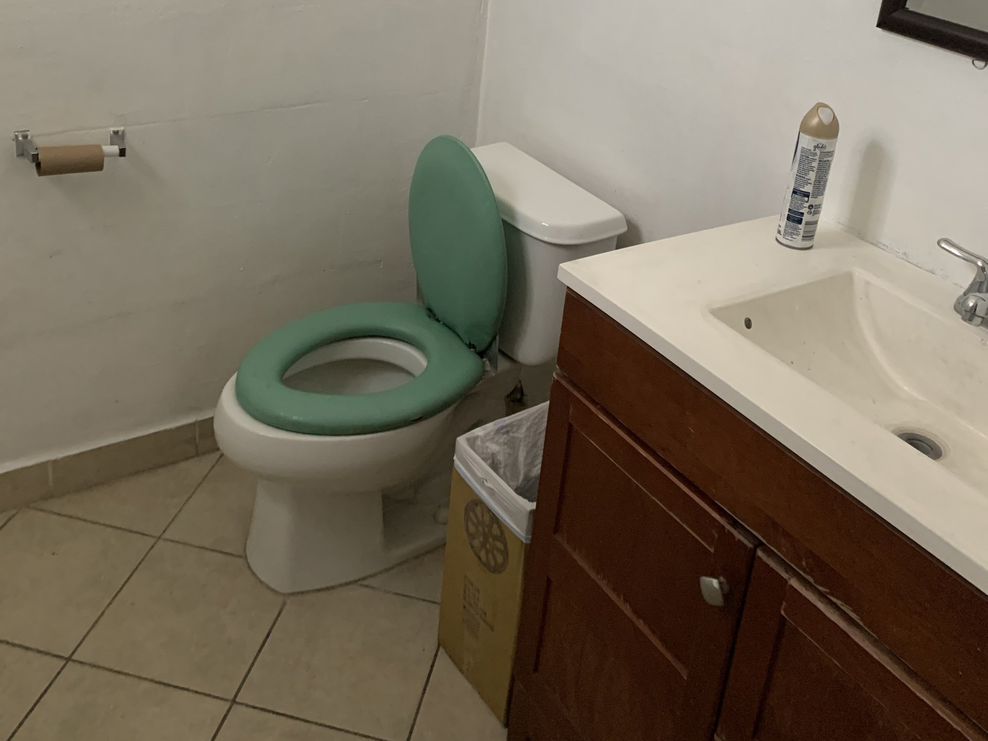 Small bathroom with mint-green toilet, wood vanity, and beige tile floor