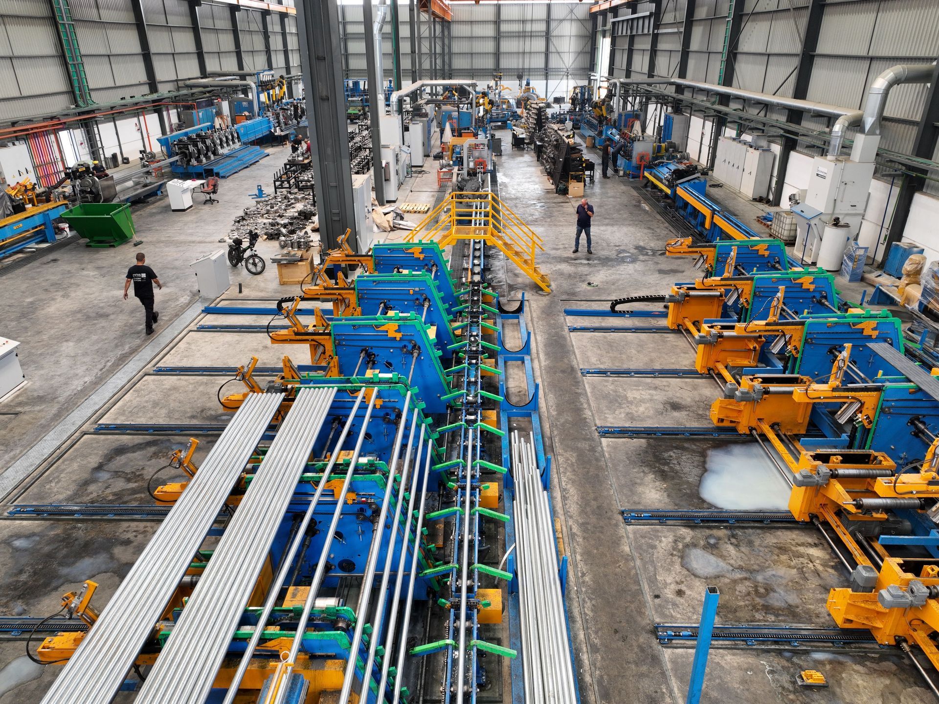 Large factory floor with rows of blue and yellow industrial machinery and a central assembly line