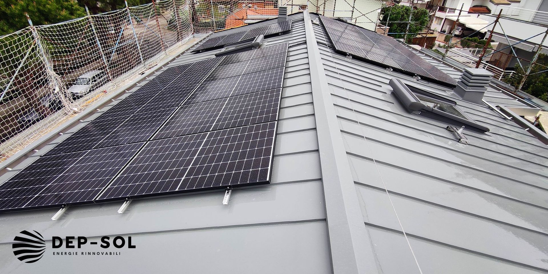 Pannelli solari installati su un tetto in metallo grigio con una fascia bianca tra le sezioni.