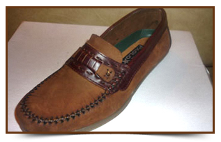 Zapato sin cordones de piel marrón con costuras decorativas y correa, mostrado sobre una superficie blanca.