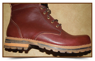 Bota de trabajo de cuero granate con suela color canela, vista lateral sobre un fondo beige.