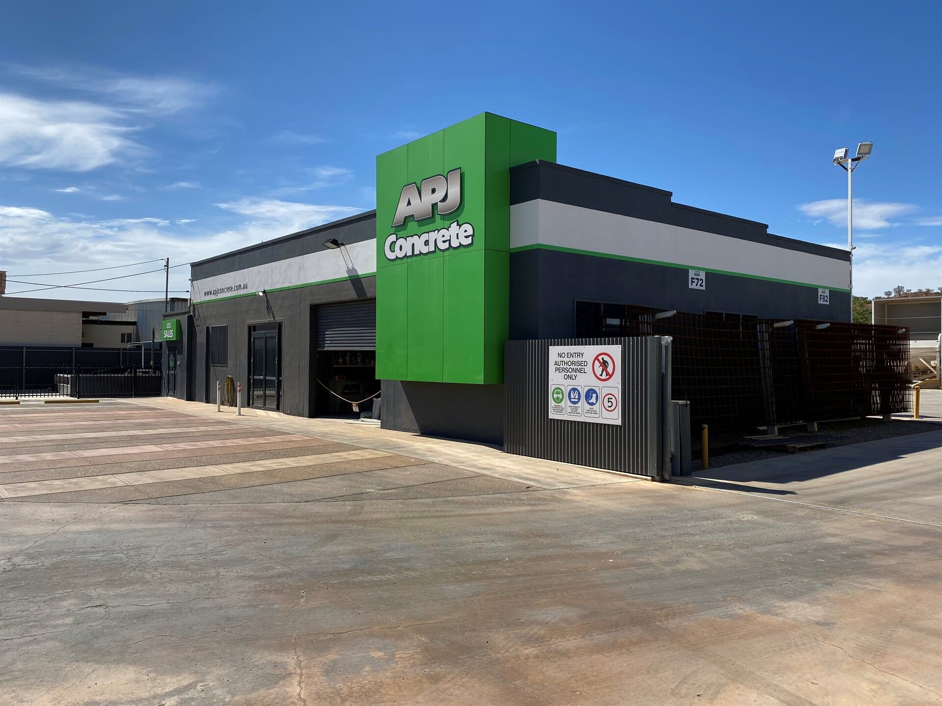 A Building With a Green Sign That Says Api Concrete on It — Bluey's Signs in Ciccone, NT