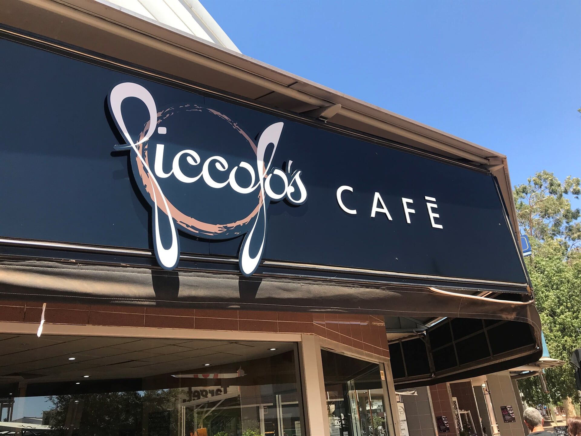 A Sign for Piccolo 's Cafe is Hanging From the Side of a Building — Bluey's Signs in Ciccone, NT