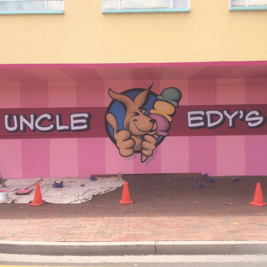 A Pink and Yellow Building With a Bunny Holding an Ice Cream — Bluey's Signs in Ciccone, NT