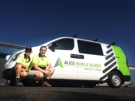 Two People Sit in Front of an Alice Mobile Blinds Van — Bluey's Signs in Ciccone, NT Two People Sit in Front of an Alice Mobile Blinds Van — Bluey's Signs in Ciccone, NT