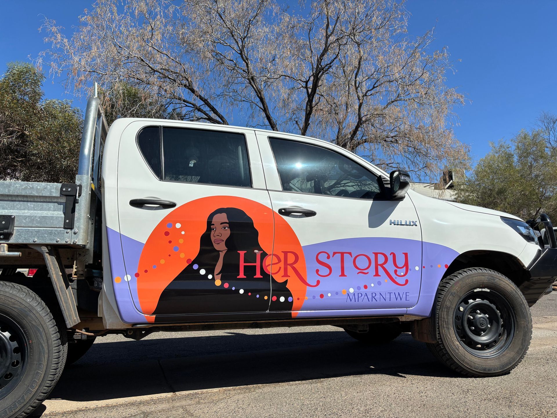 A white truck with a picture of a woman on the side is parked on the side of the road  — Bluey's Signs in Ciccone, NT