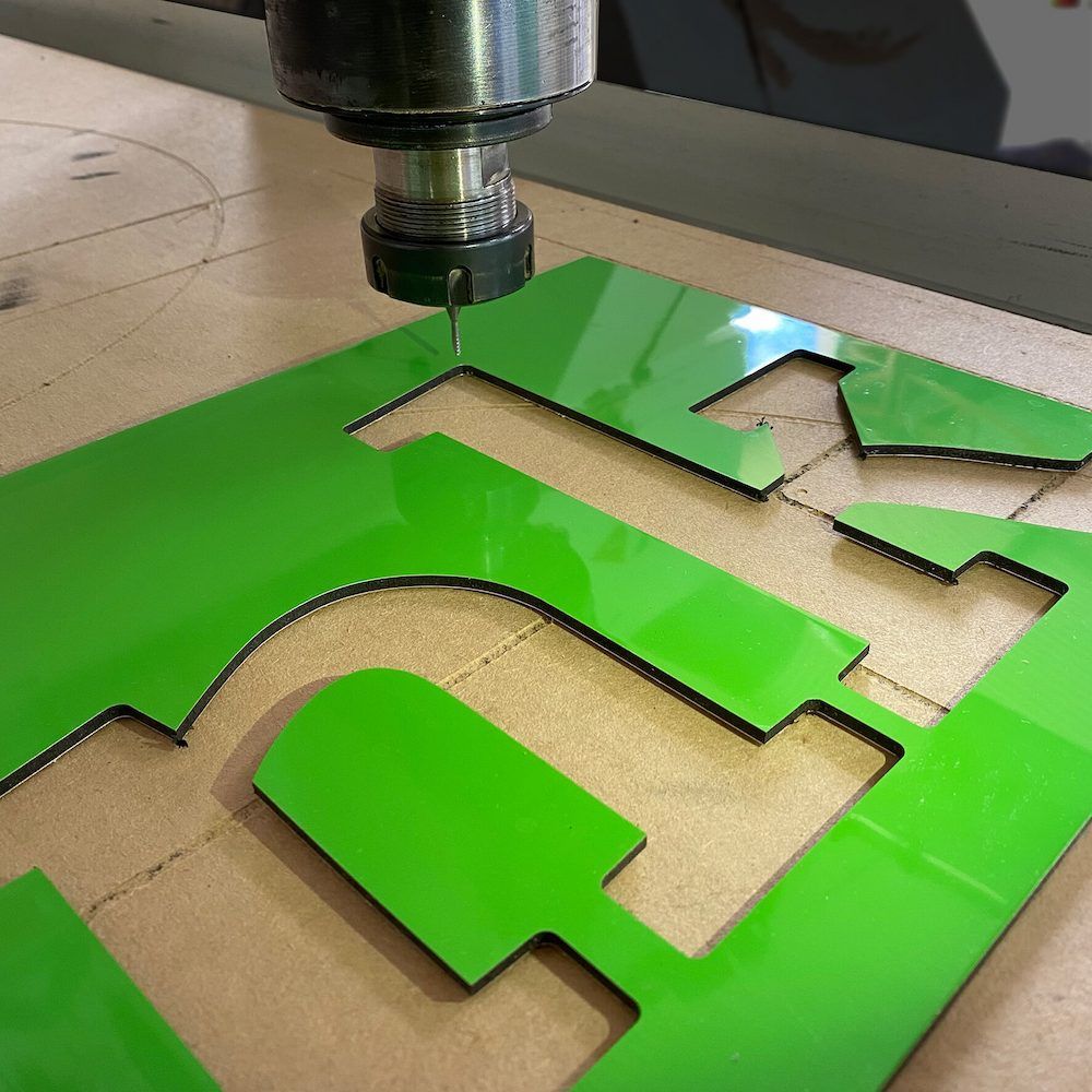 A Green Letter T is Being Cut by a Machine — Bluey's Signs in Ciccone, NT A Green Letter T is Being Cut by a Machine — Bluey's Signs in Ciccone, NT