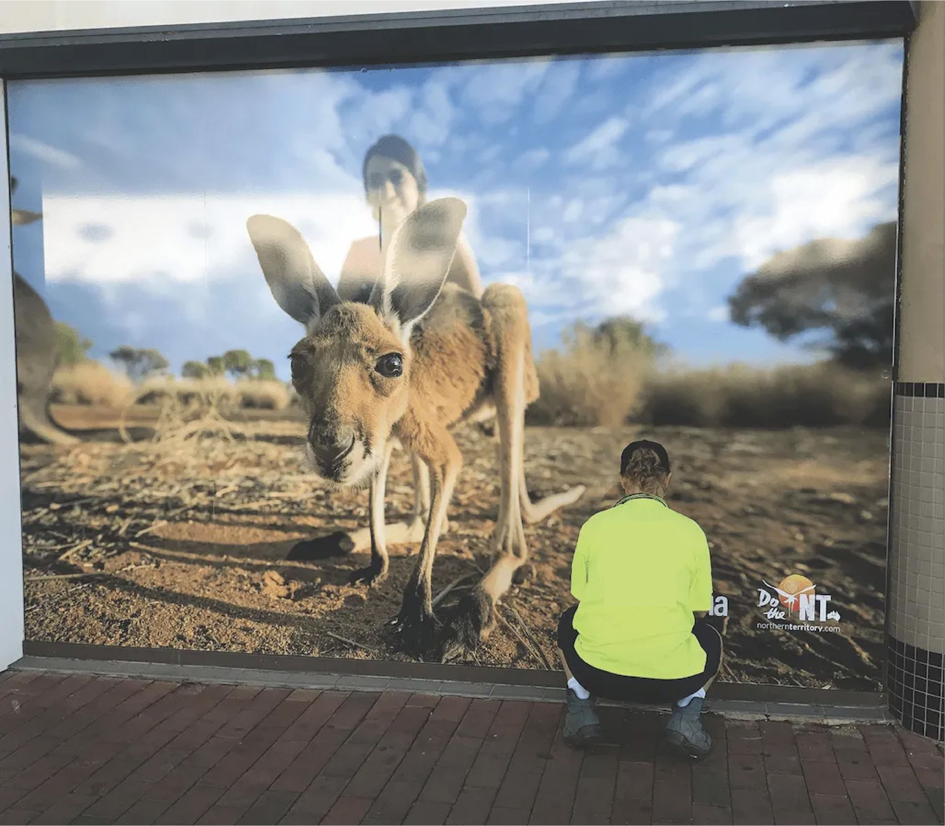 A Man Kneeling in Front of a Wall With a Kangaroo on It — Bluey's Signs in Ciccone, NT