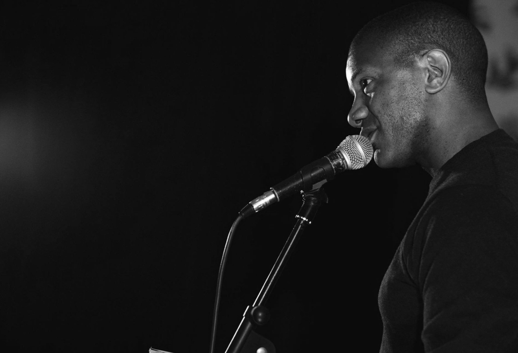 Rick at the microphone performing and gesturing with his right hand