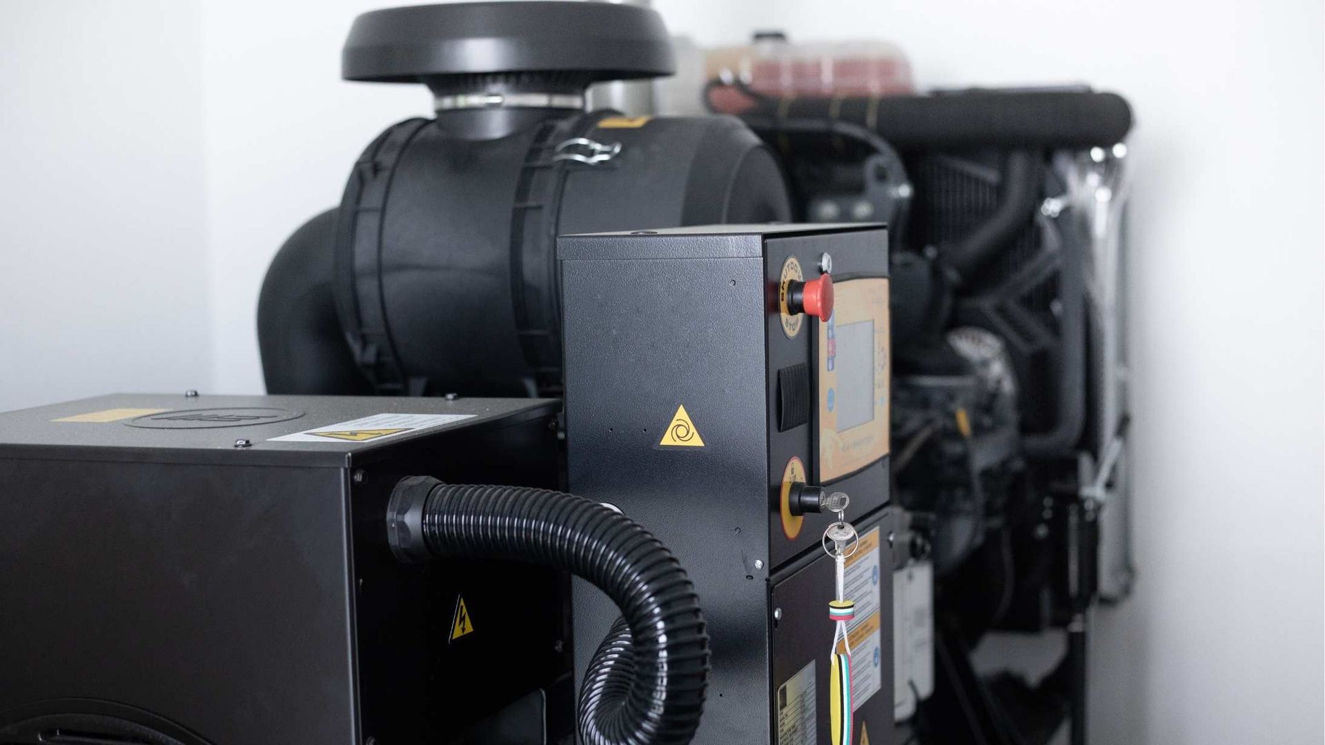 Black industrial machinery with vents and warning labels in a bright room