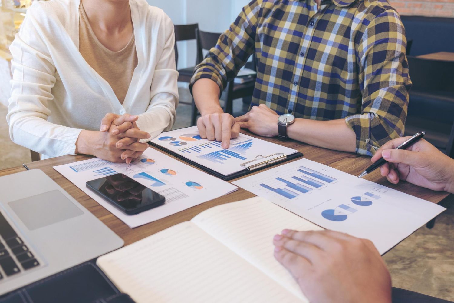 Team reviewing charts and graphs around a laptop during a business meeting