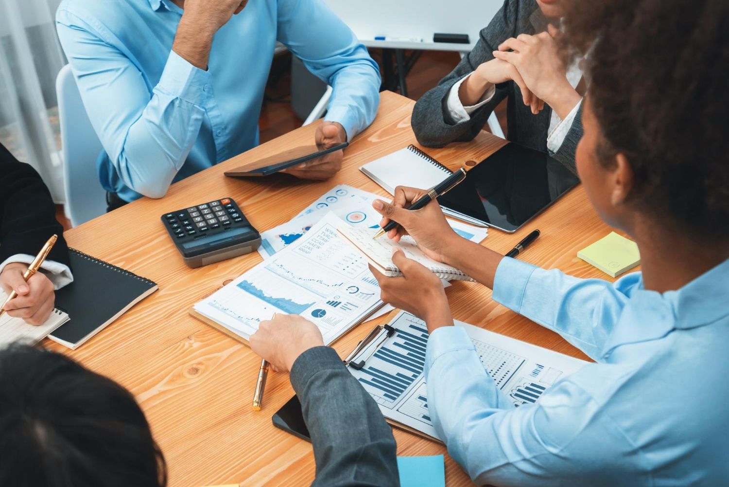 People in business attire reviewing charts and documents around a conference table