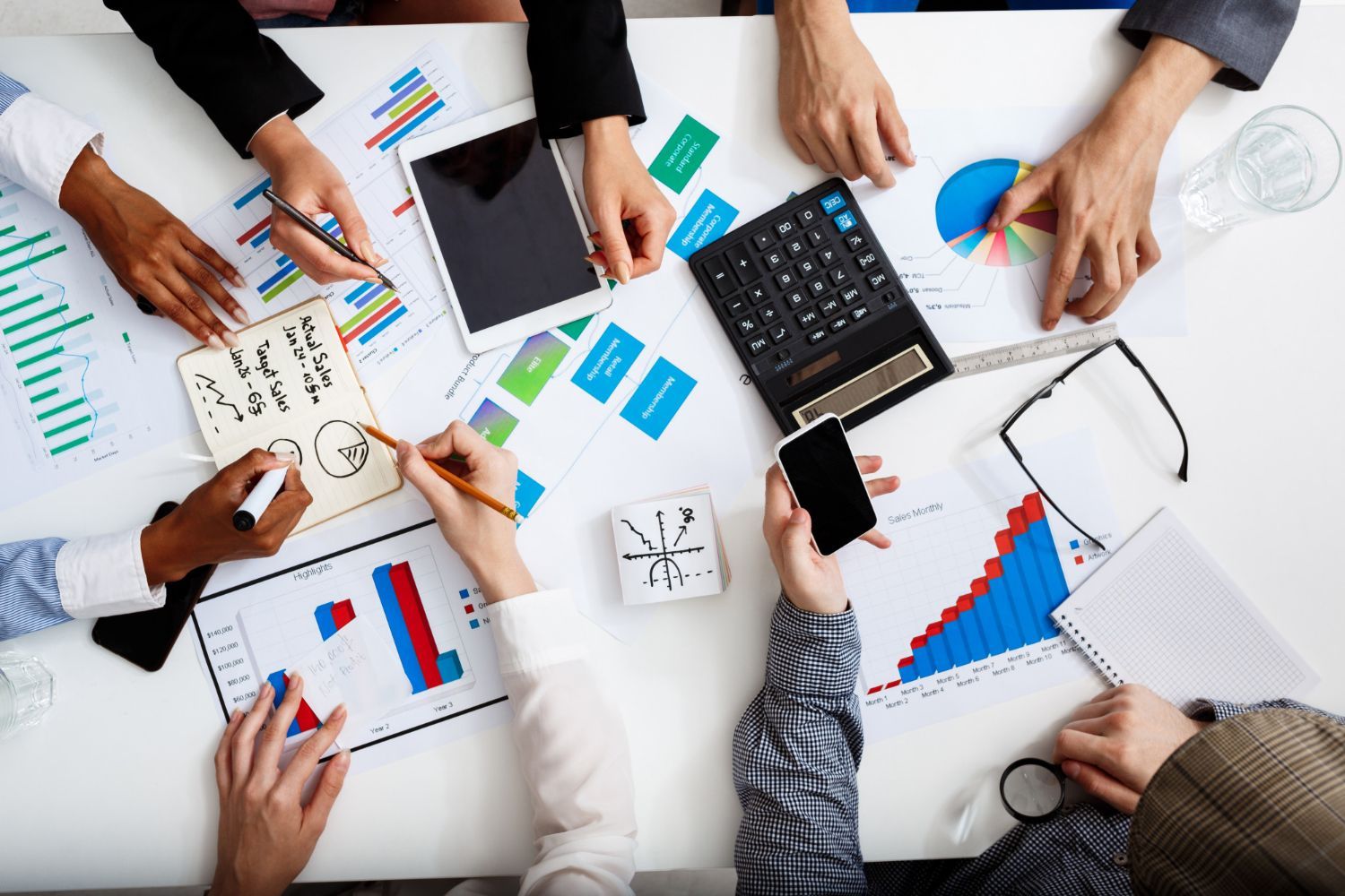 Team reviewing charts and graphs around a laptop during a business meeting