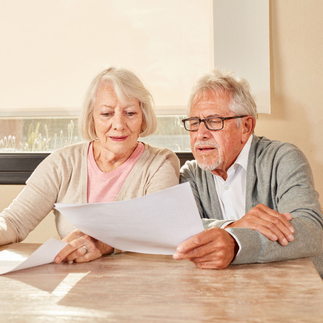 Older couple reading papers together at a table in a bright room