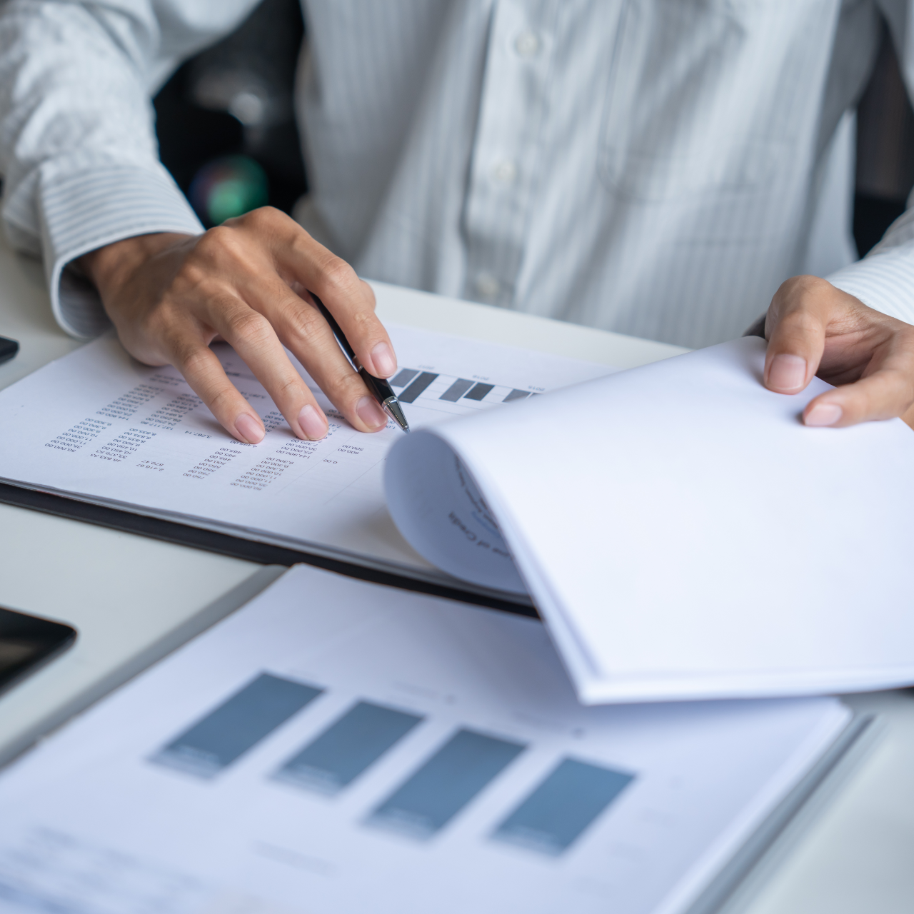 Hands reviewing business charts and graphs on printed documents at a desk