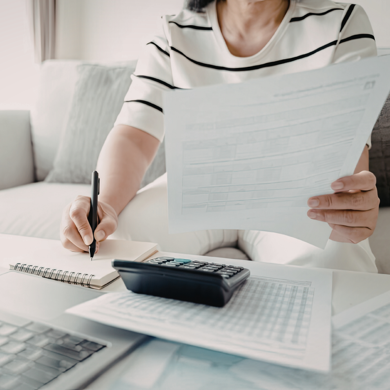 Person at a desk filling out a form with a pen and calculator nearby