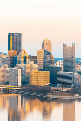 City skyline with high-rise buildings reflected in calm water at sunset