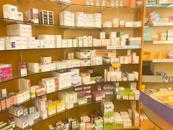 Scaffali pieni di medicinali e prodotti per la salute di vario genere in una farmacia o parafarmacia.