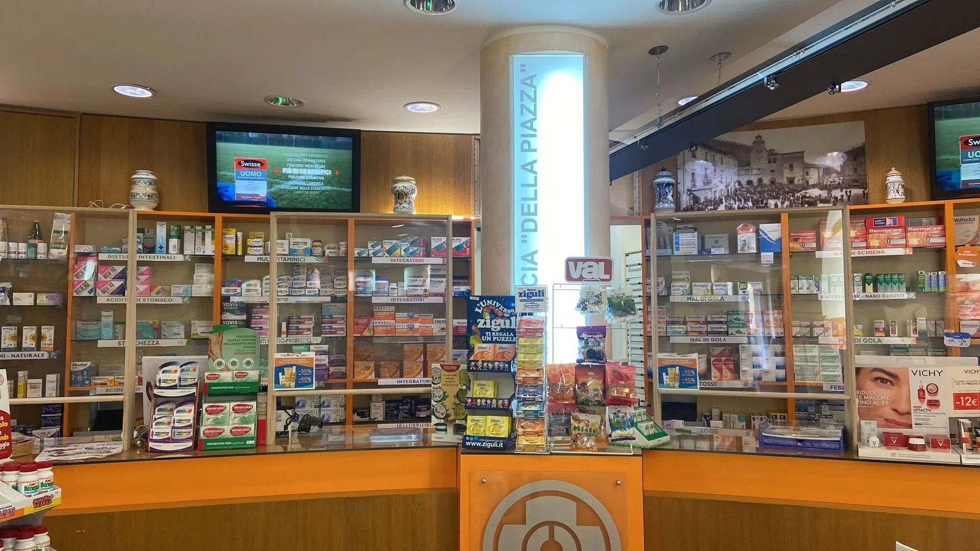 Bancone del minimarket con espositori di snack, bevande e un televisore montato sopra