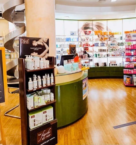 Luminoso bancone da farmacia con scaffali pieni di prodotti per la cura della pelle in un negozio con pavimento in legno.