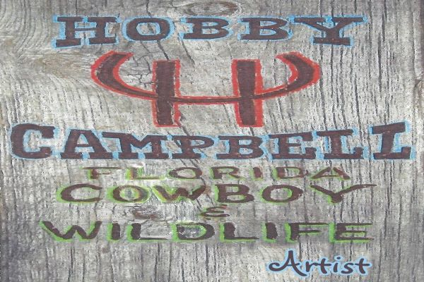 Wooden sign reading “HOBBY CAMPBELL DESOTO COUNTY WILDLIFE” with a deer antler logo and “Artist” at bottom right