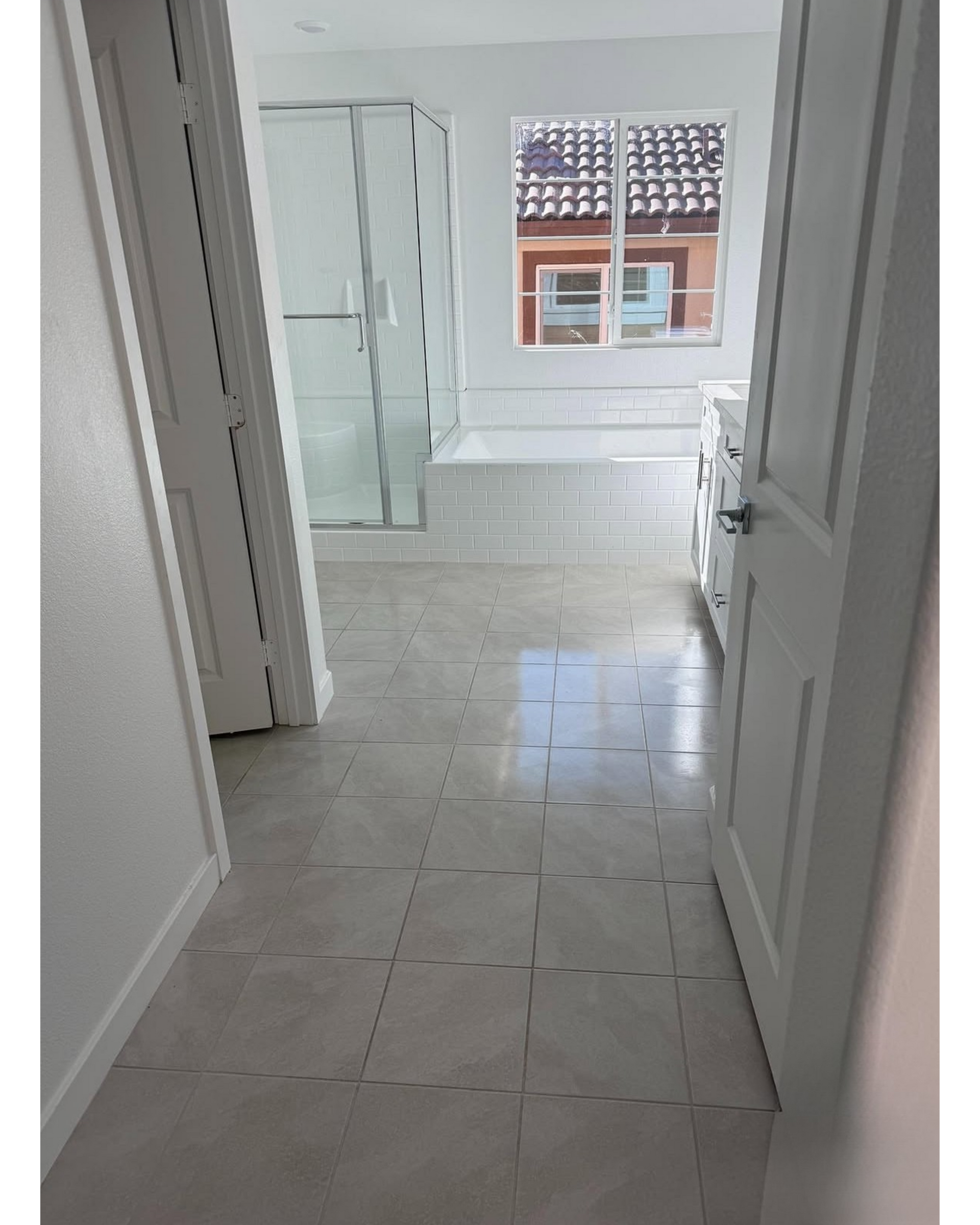Open doorway with a screen door, showing a concrete patio and yard outside from inside a room.